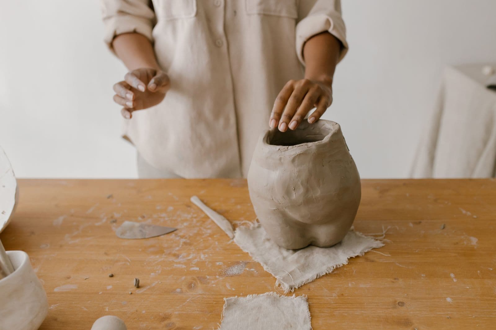 Ceramic artist shaping a handmade vessel at a workshop table